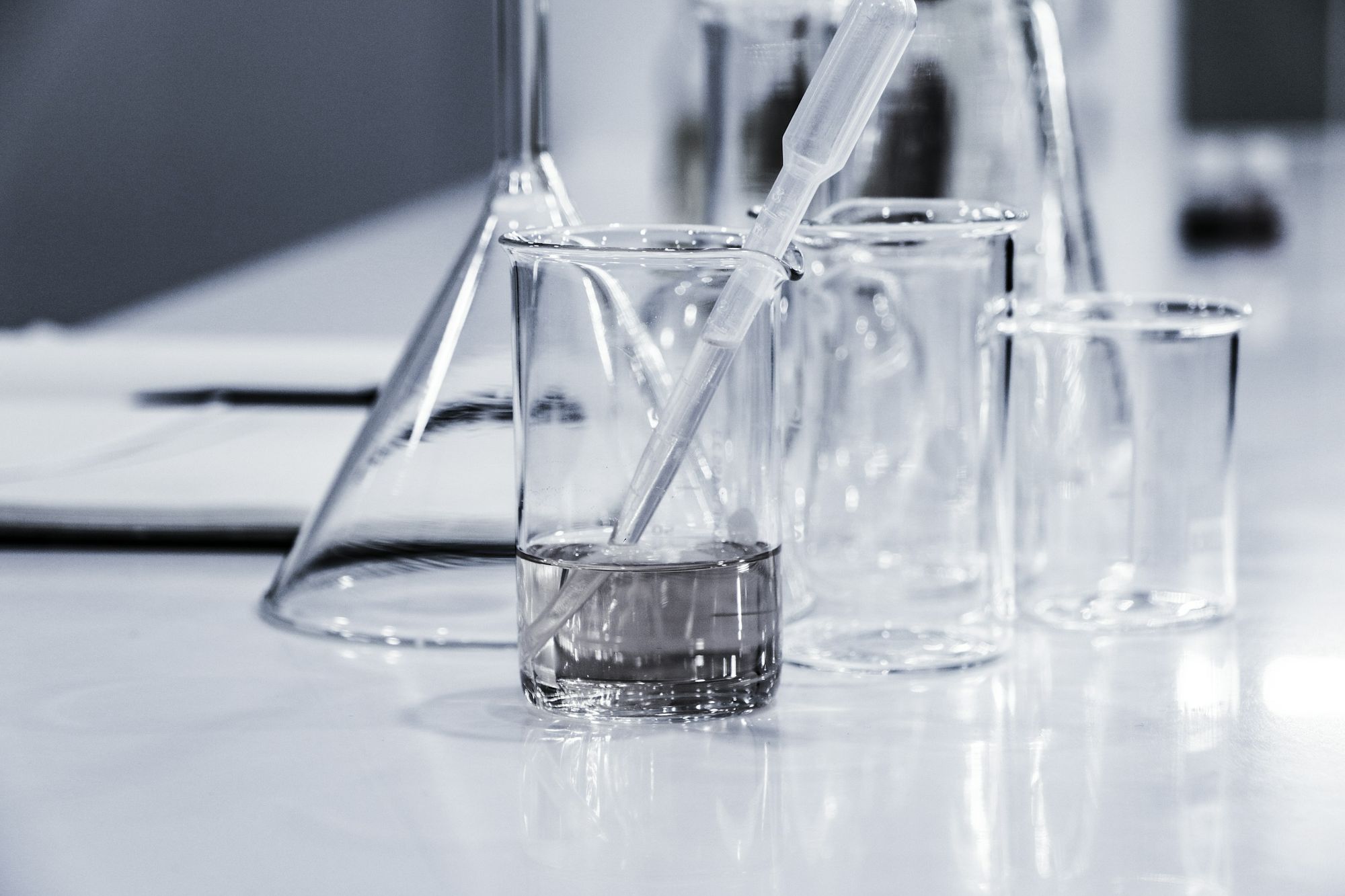 Laboratory glassware and a pipette on a white bench